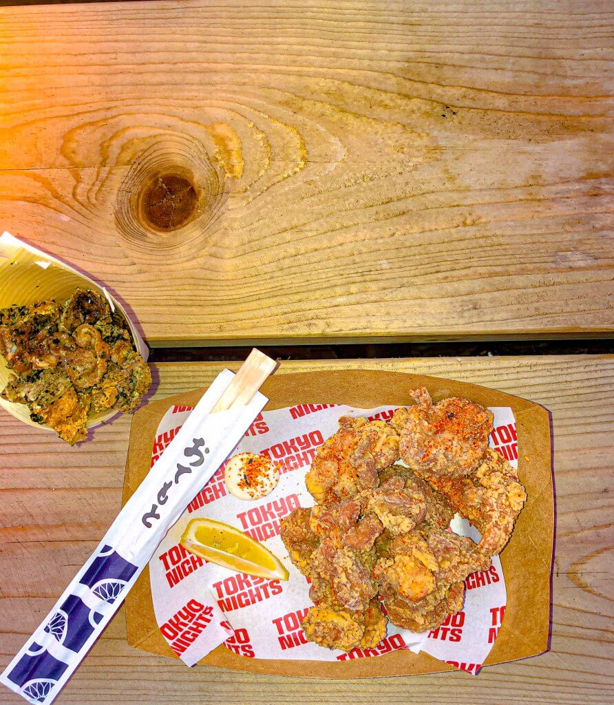 Karaage Chicken and Seaweed and Salt Chicken Skins with chopsticks from Tokyo Nights in brown tray on brown table - Bird's Eye View