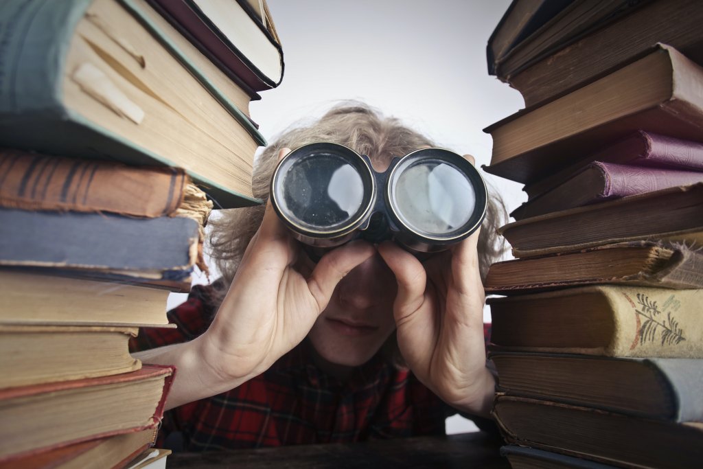 Person with binocular between books