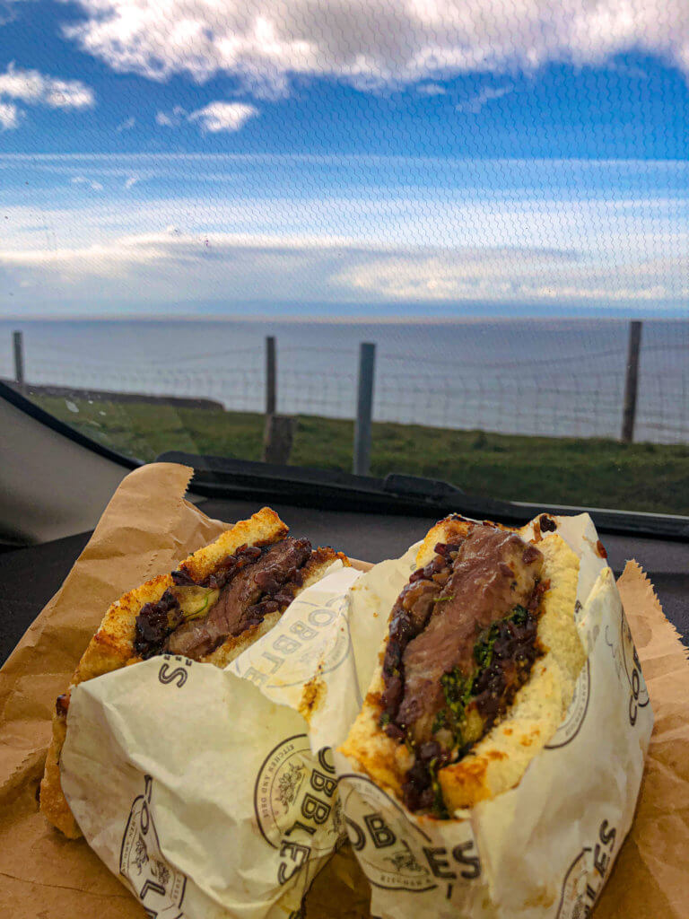 Steak sandwich from Cobbles kitchen with sea and clouds in background 