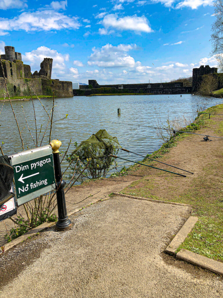 No fishing sign on Caerphilly Castle lake with fishing rods