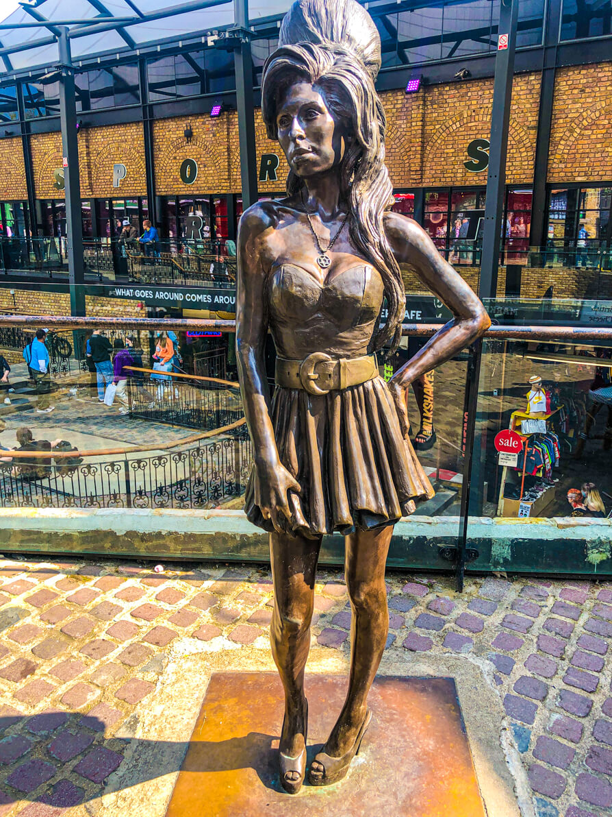 Amy Winehouse Statue Camden in centre of photo with Camden Market building in background