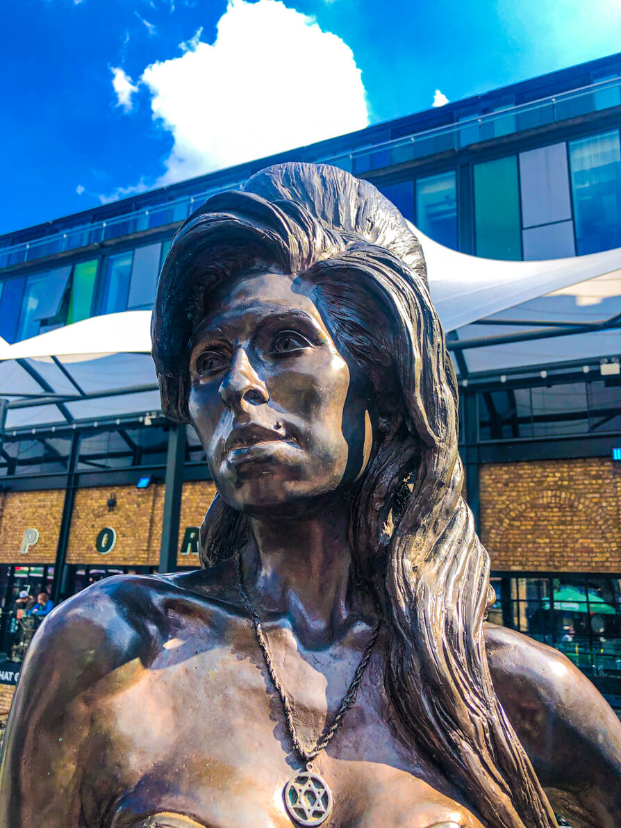 amy winehouse camden statue from below the head point of view of the statue with blue sky in background.