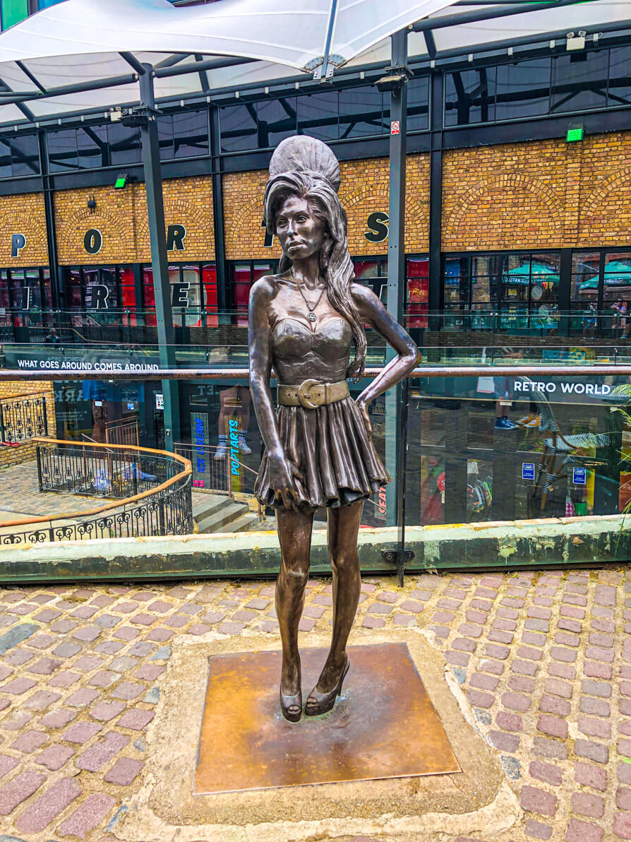 Amy Winehouse camden statue in Camden Market in centre of image with sports direct building in background