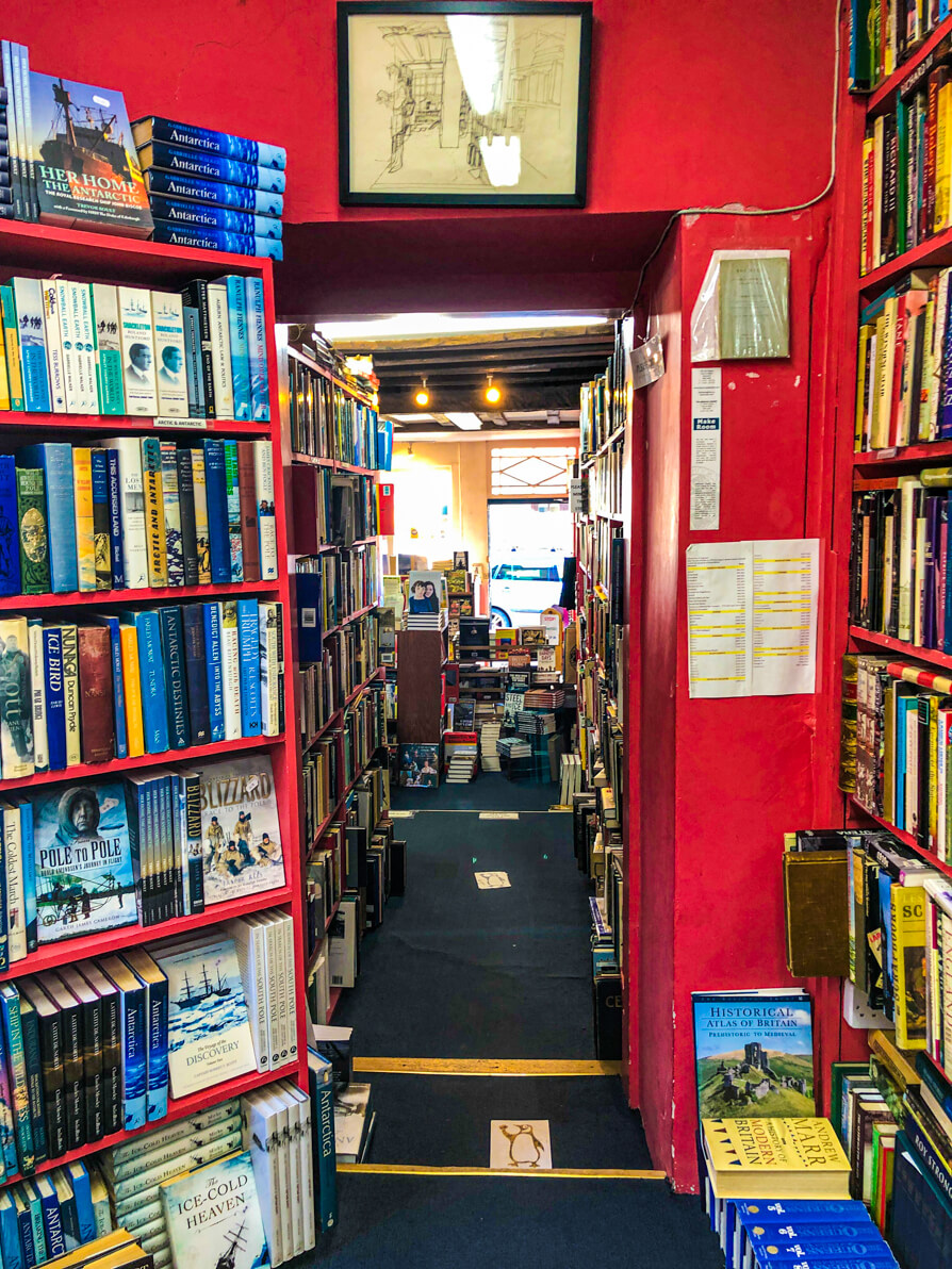 The Addyman Annexe red corridor with books either side and on the floor. Hay on Wye bookshop tour