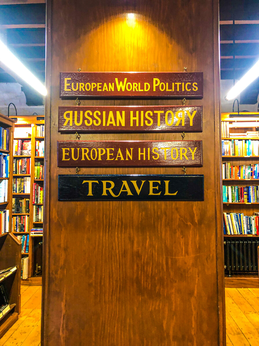 Side of bookshelf signs saying Travel, European History, Russian History, European World Politics in Richard Booths Cinema Bookshop in Hay-on-Wye
