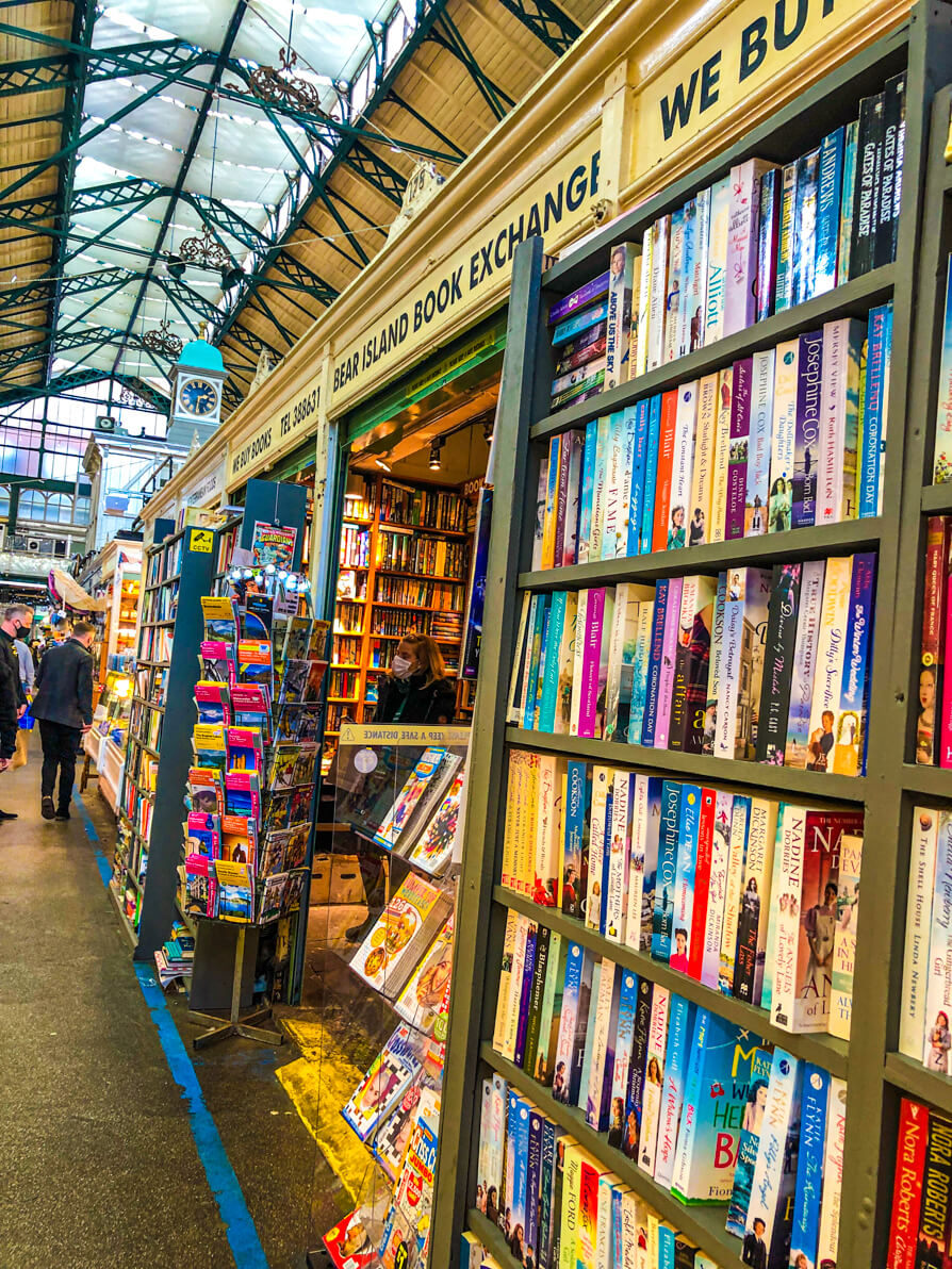 Image from the right hand side of Bear Island Book Exchange in Cardiff Market. Image shows the bookshop to the right of the picture and the rest of the market aisle to the left.