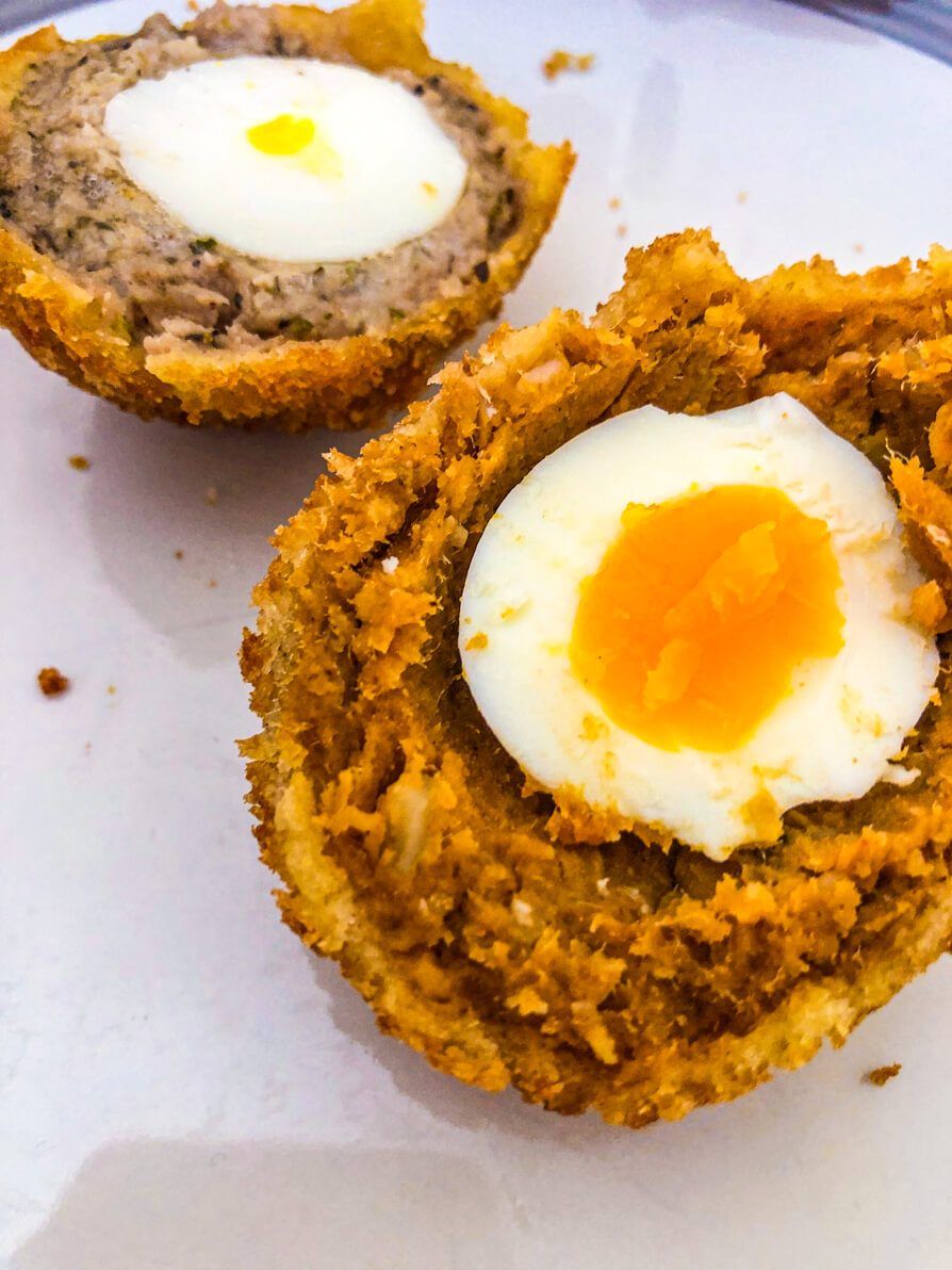 Image of two halves of a large scotch egg on a white plate