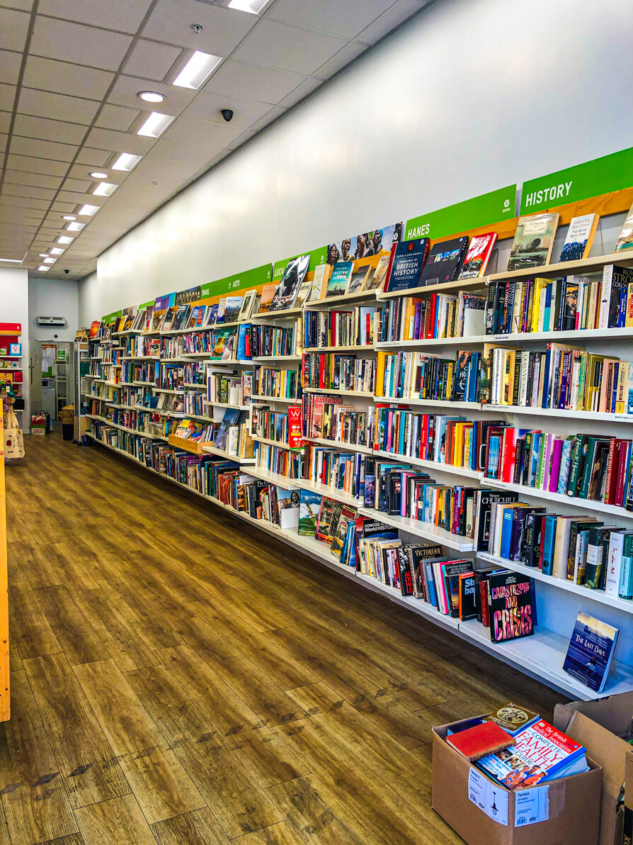 Inside of Oxfam bookshop in Cardiff. The right of the picture has the shelves across the entire shop wall full of books and the left of the picture is the wooden floor
