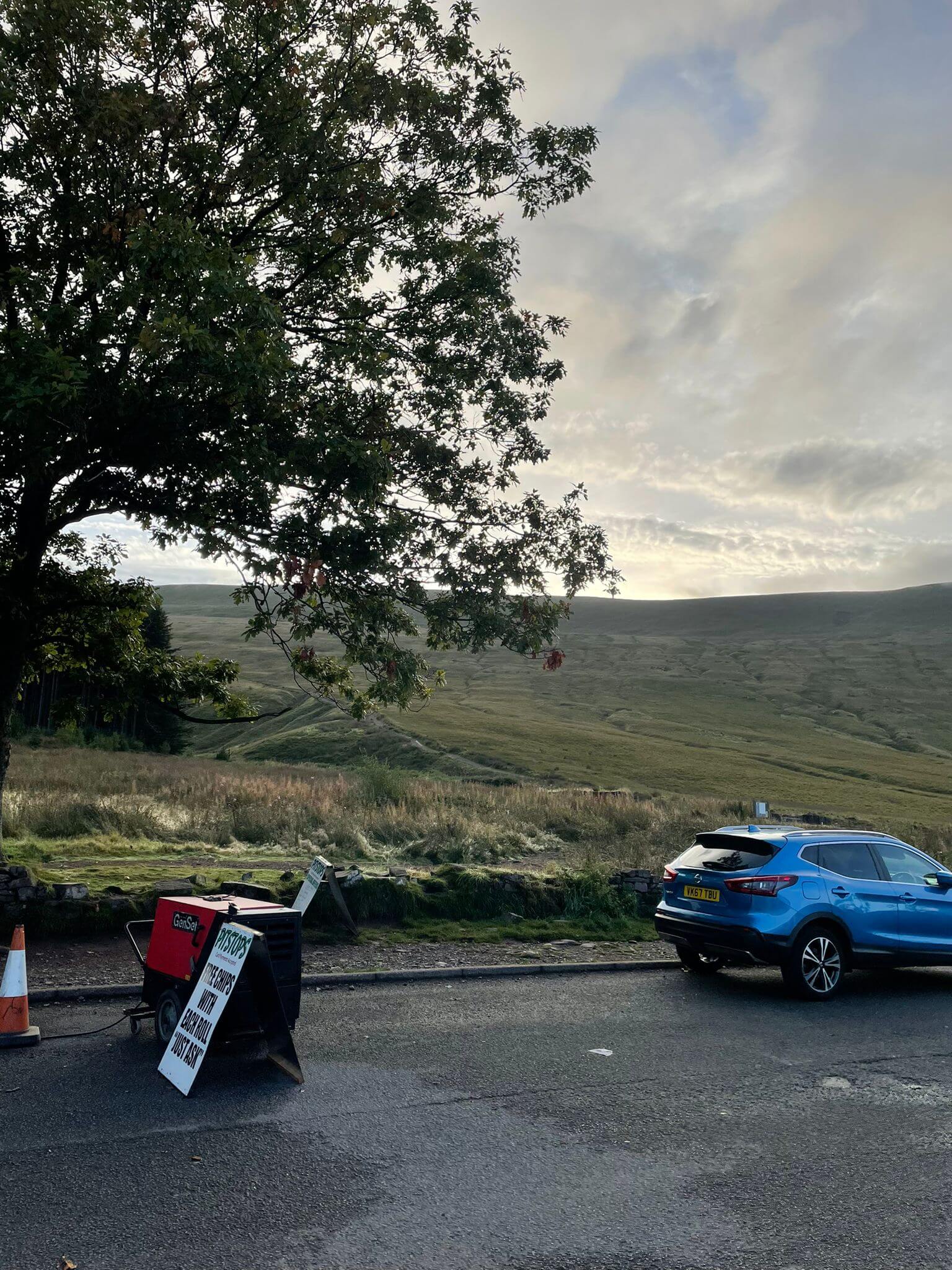 Pen Y Fan Car Park with blue car and Pitstops sign in front with tree in back