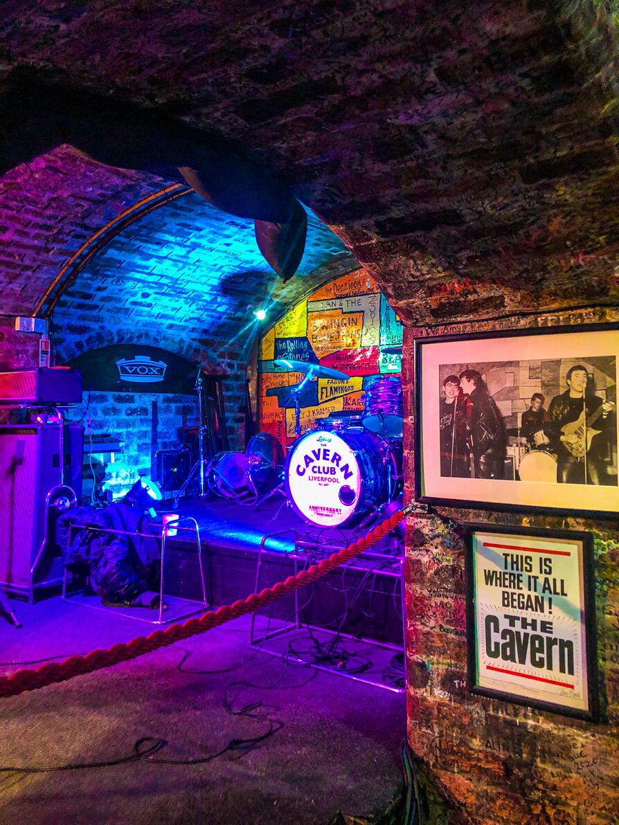 Interior of The Cavern Club stage with The Beatles poster on right hand side wall in Liverpool
