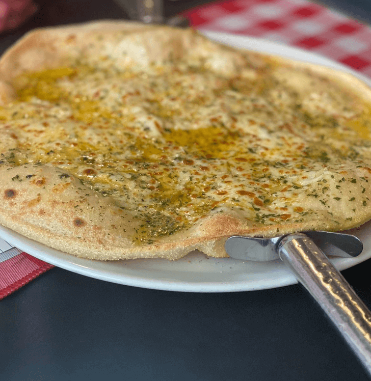 Image of garlic flat base bread on white plate with pizza cutter handle showing beneath bread in Little Italy, Aberystwyth 