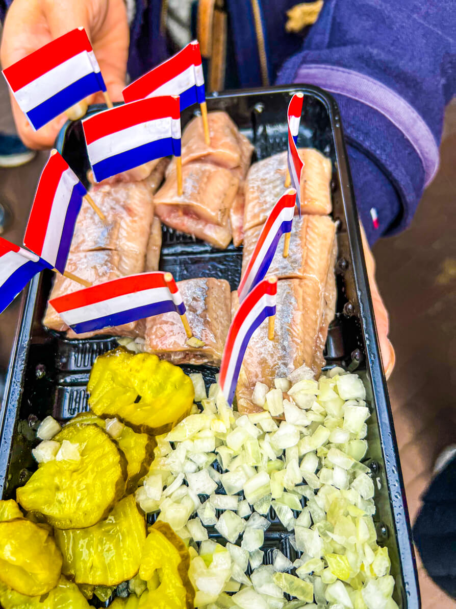 Image of Raw herring with pickles and onion and a Netherlands flag on a stick in each piece of Herring in Amsterdam