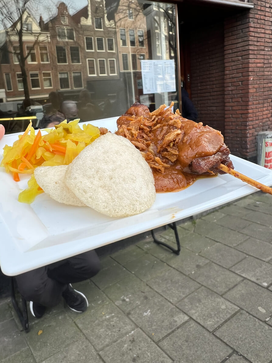 Image of satay and crackers on white plate outside the restaurant in Jordaan Amsterdam