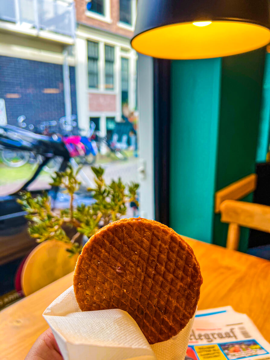 Stroopwaffel in white napkin perched above a table and infront of window at local cafe in Jordaan Amsterdam