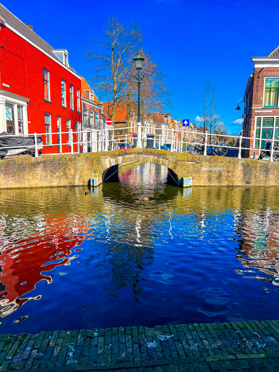 Canal front with bridge and red house in Delft Netherlands