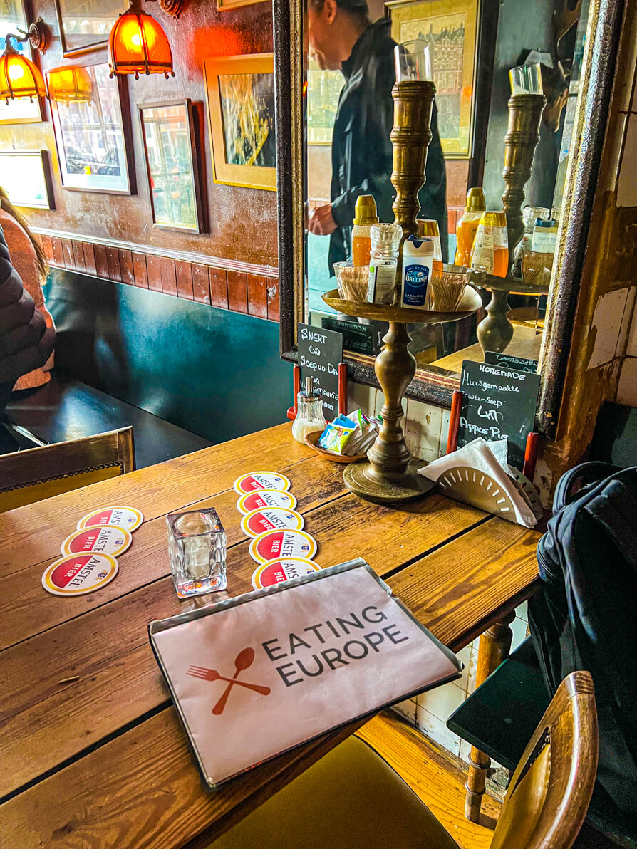 Image is in Cafe Papeneiland on the Eating Europe Amsterdam Food Tour with Eating Europe sign on the table