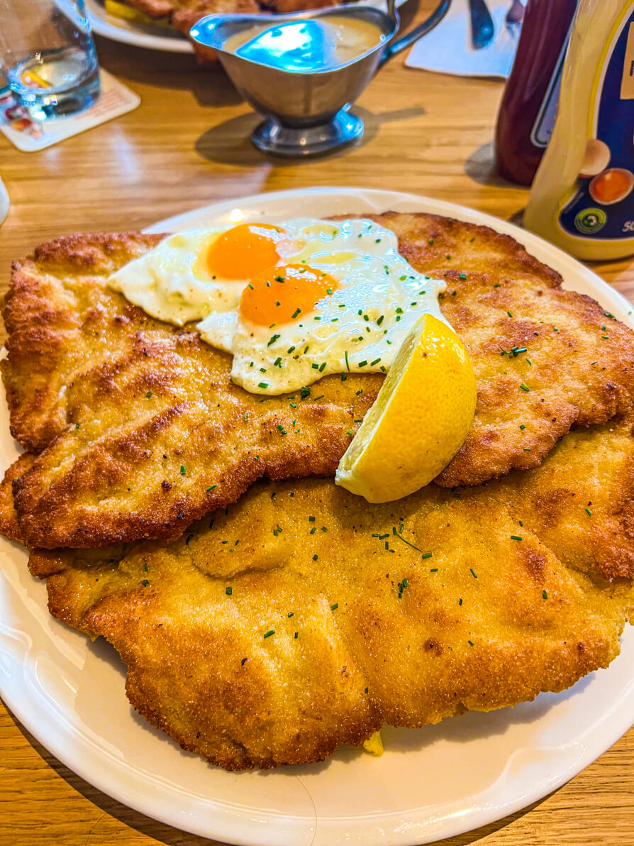 Schnitzel with two fried eggs and lemon on top in Andy's Munich Germany