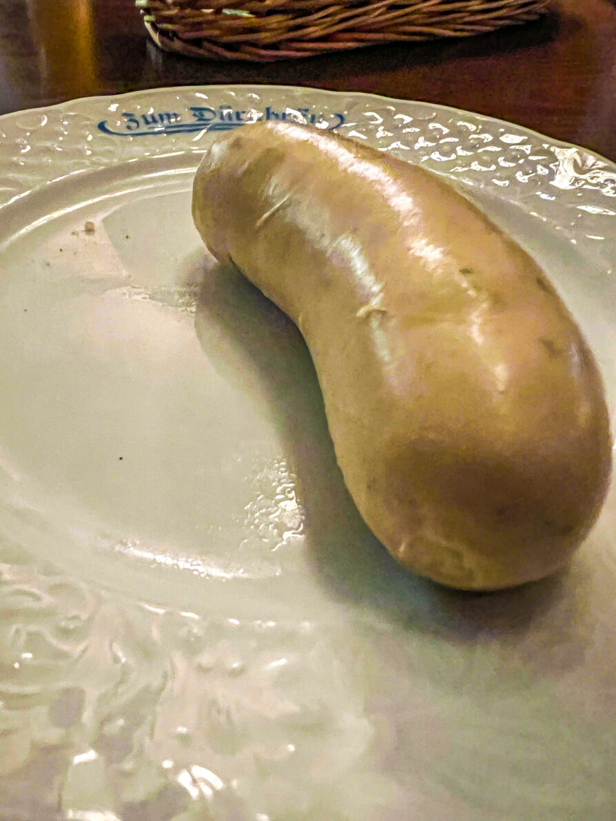 Up close image of a single weisswurst on white plate in Munich Germany