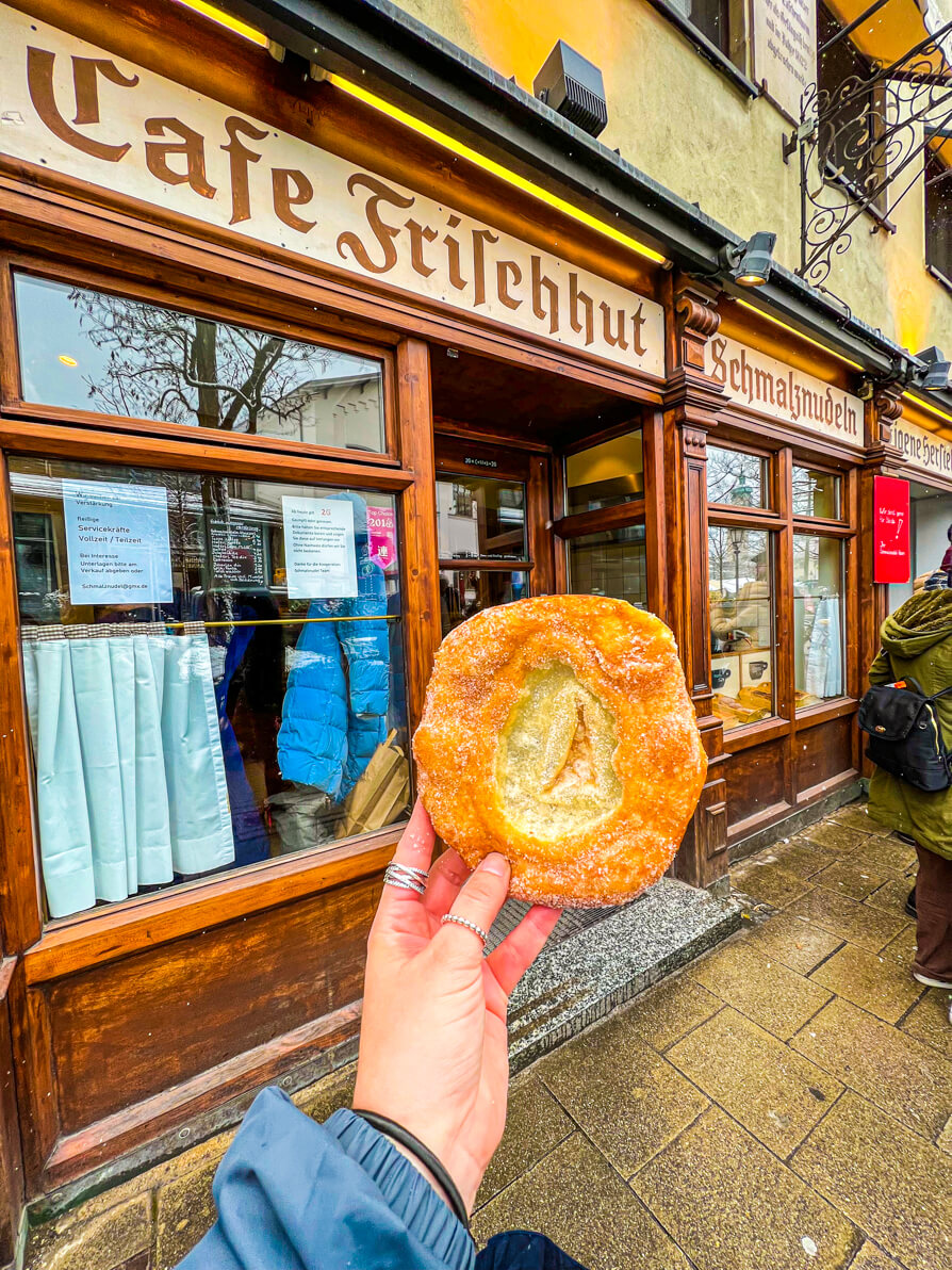 Shireen's left hand holding up the Schmalznudel in front of the bakery in Munich Germany Food Tour with Fork and Walk Tours