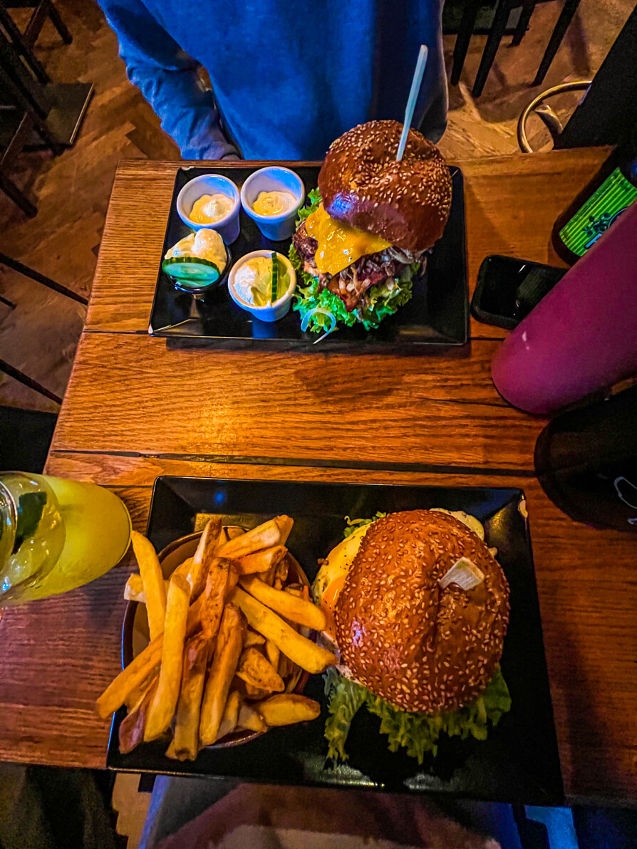 Bird's eye view of two burgers on black plates on a wooden table in Kuhmuhne restaurant in Nuremberg Germany