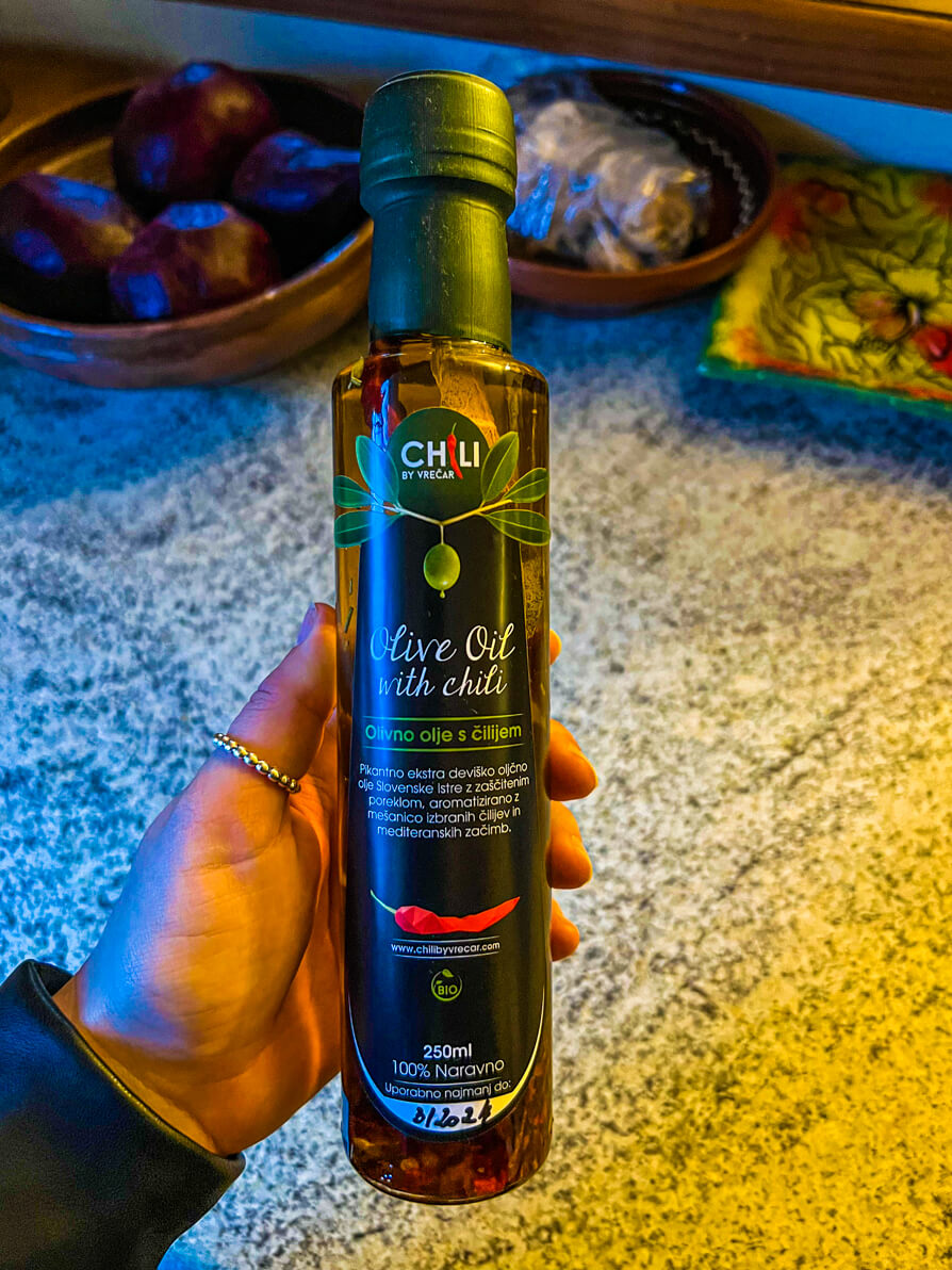 Image of Shireen's left hand holding up an olive oil with chilli in a bottle