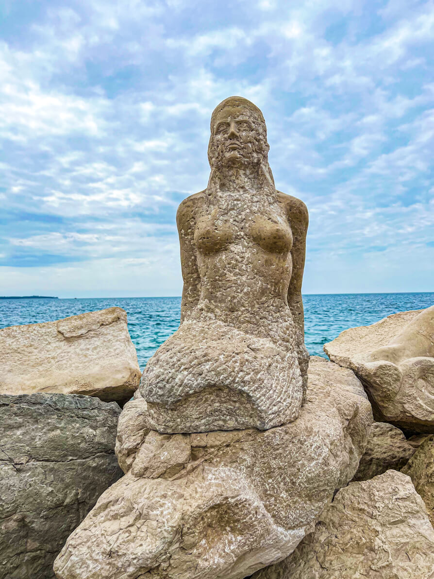 Image of the mermaid statue in Piran Slovenia with ocean and sky in background