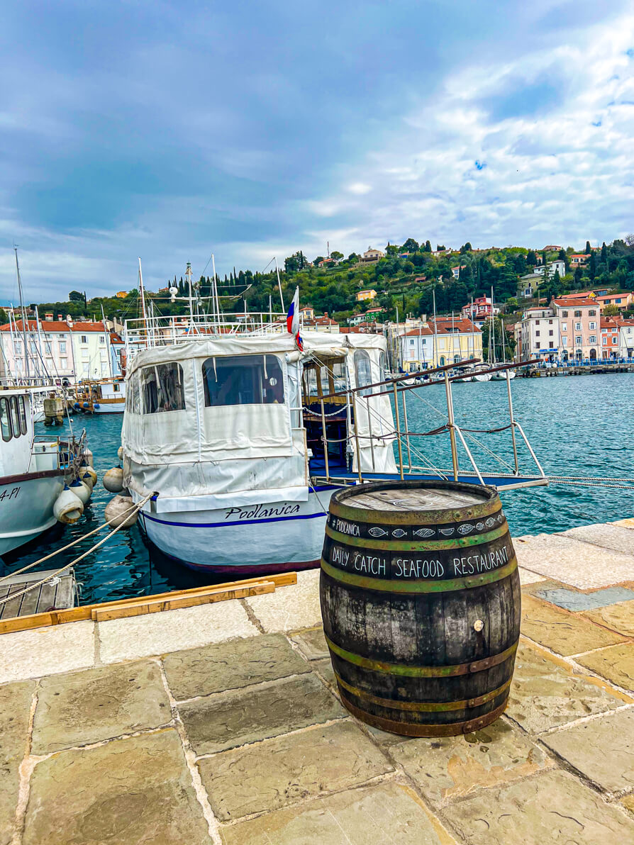 Image of Podlanica boat restaurant with barrel in front of the sign in Piran