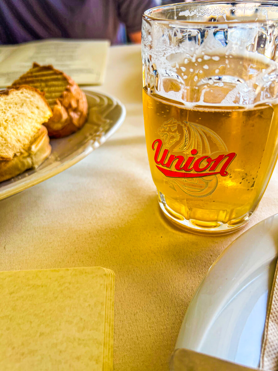 Image of Union beer in a glass mug with a bowl of bread on a beige table in Slovenia