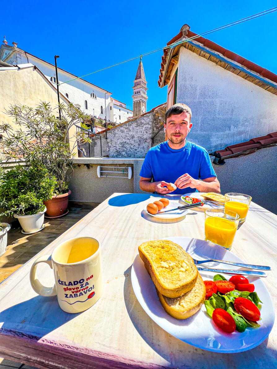 Image of Scott eating breakfast on the table on the roof terrace of Traditional Piran House accommodation in Piran Slovenia