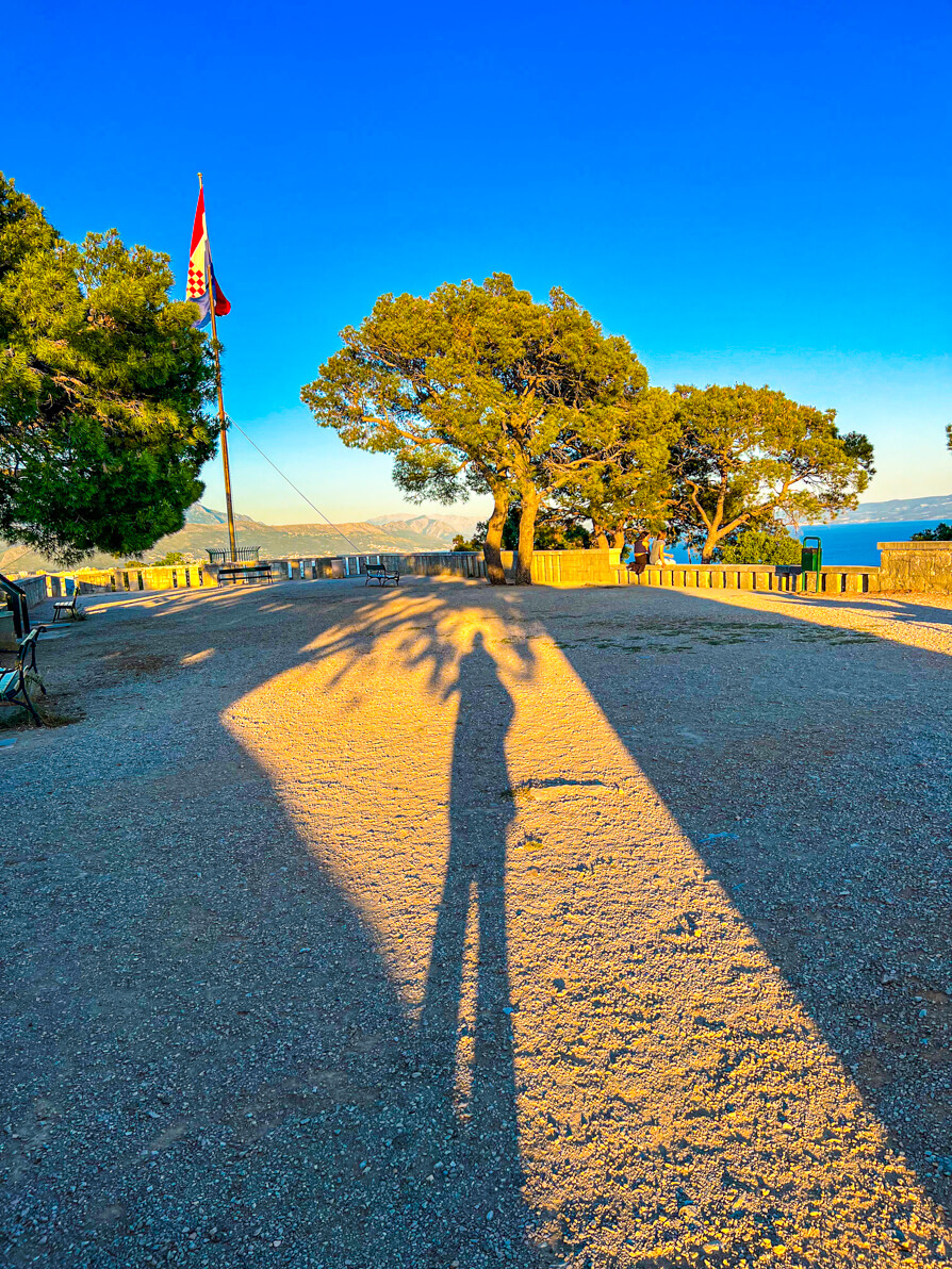 Image of Shireen's shadow at the Marjan Hill viewpoint with trees and Croatia flag in background