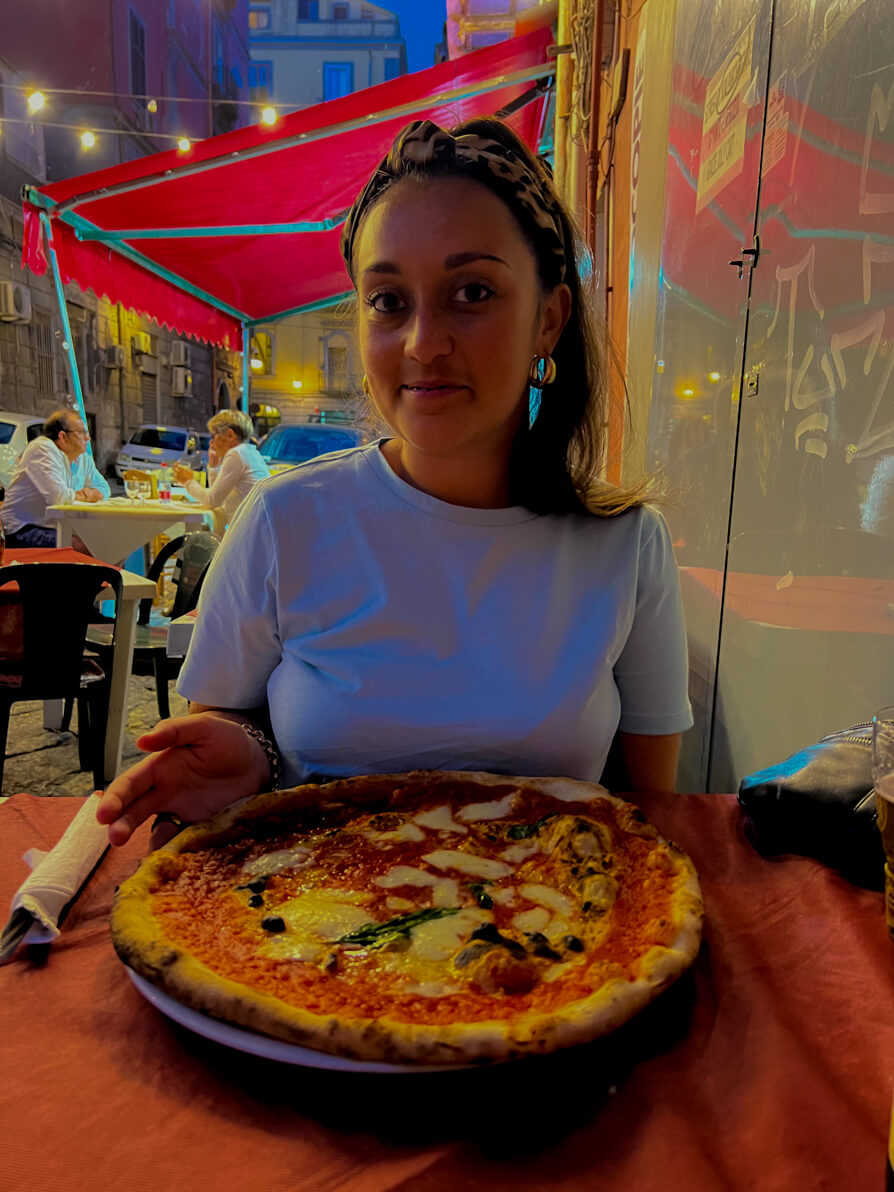 Image of Shireen with her margarita pizza on an outside table in Antica Pizzeria Del Borgo in Naples Italy