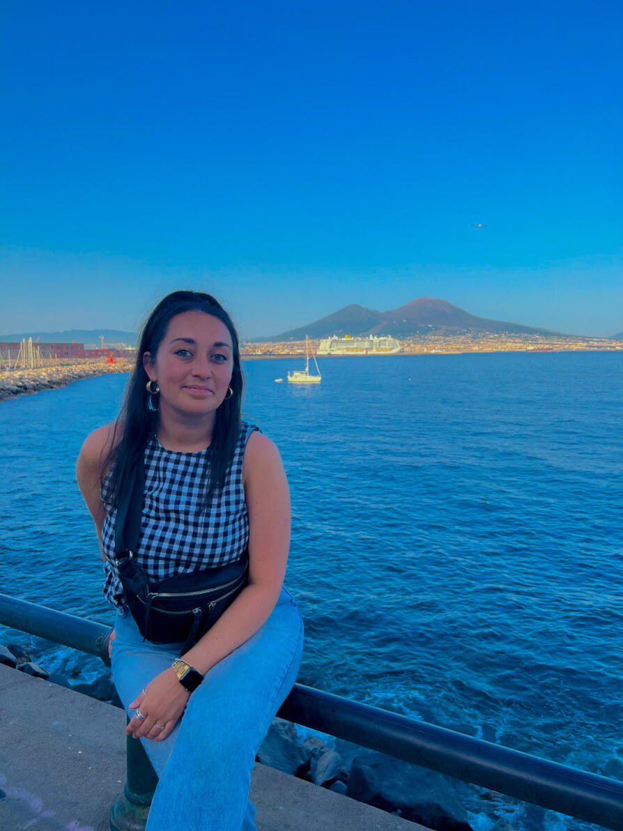 Image of Shireen sitting on Lungomare with Mt Vesuvius in background 