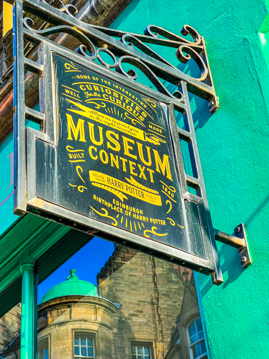 Image of Museum Context sign above the shop entrance saying 'Museum Context' with green wall in background in Edinburgh Scotland