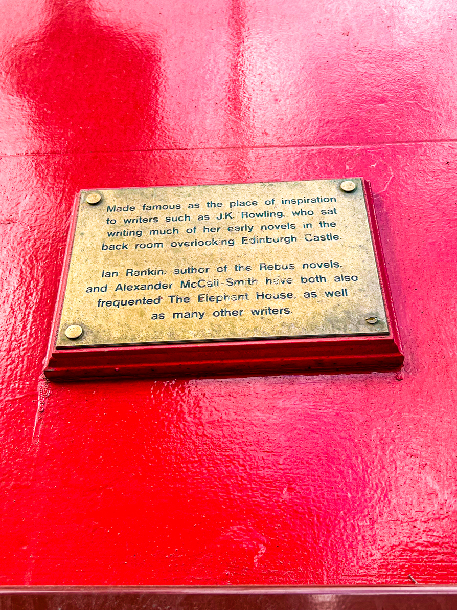 Gold plaque on red wall of Elephant Cafe giving information about writers of Edinburgh