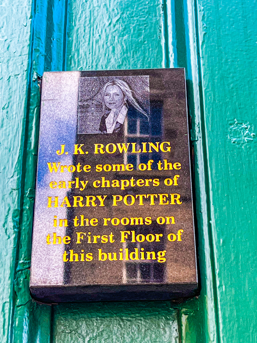 Black plaque on green wall with picture of JK says 'J.K. Rowling wrote some of the early chapters of Harry Potter in the rooms on the first floor of this building'