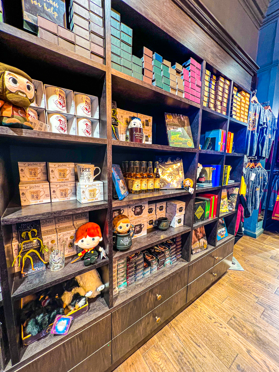 Interior of Enchanted Galaxy shows a shelf of Harry Potter things to buy like mugs and wands.