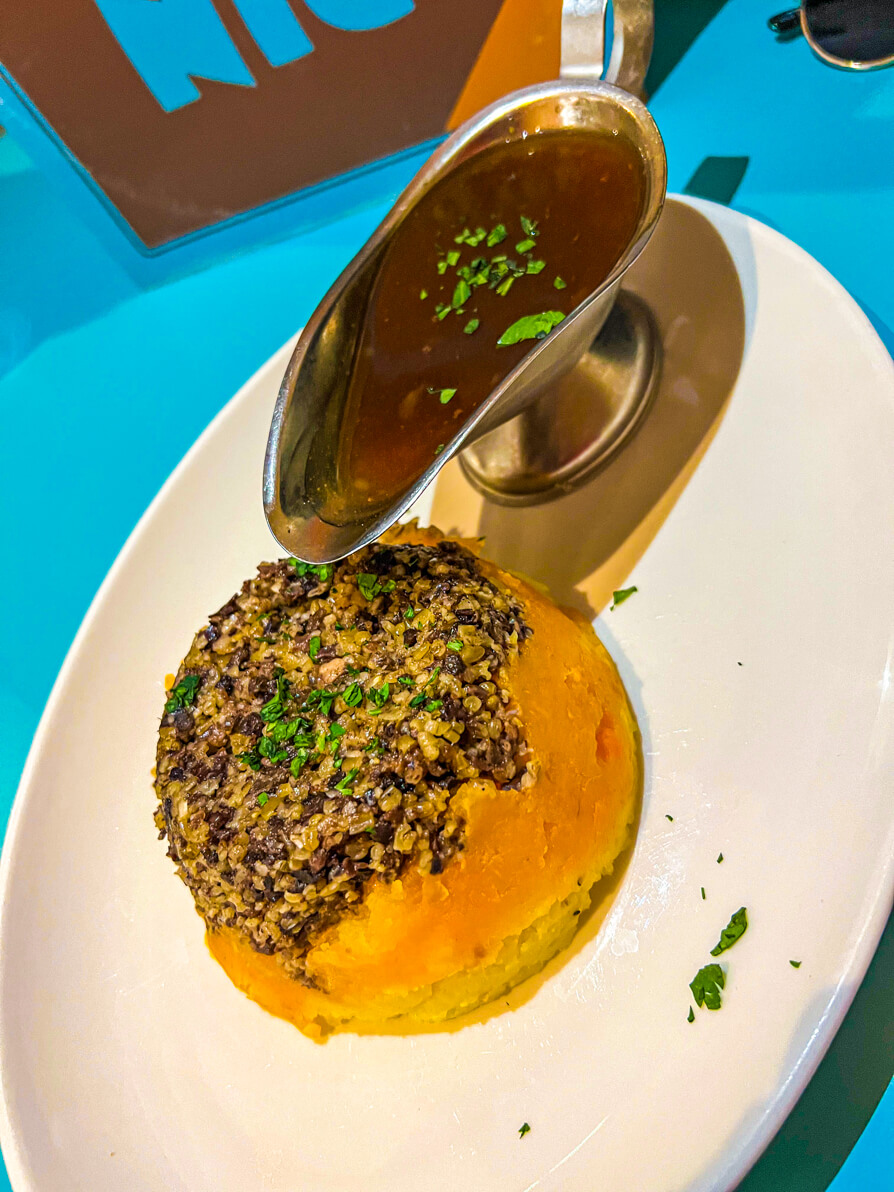 Image of Haggis Neeps and Tatties on a white plate with a silver gravy boat of gravy in Scotland