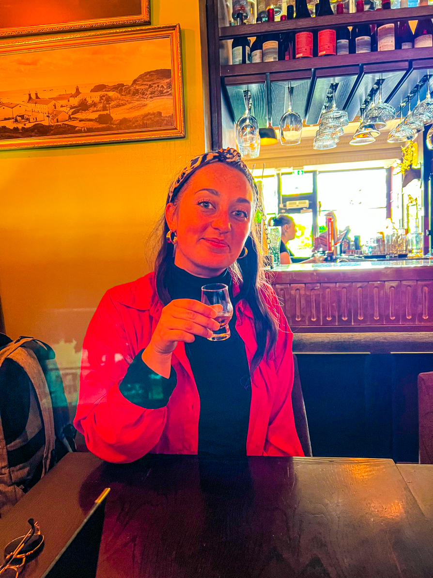 Image of Shireen holding a glass of Whiskey on the Edinburgh Secret Food Tour in Scotland
