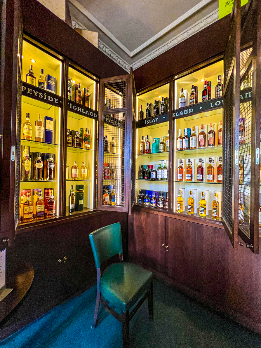 Image of Whiskey cabinet with a chair in front of a Whiskey store in Edinburgh Scotland
