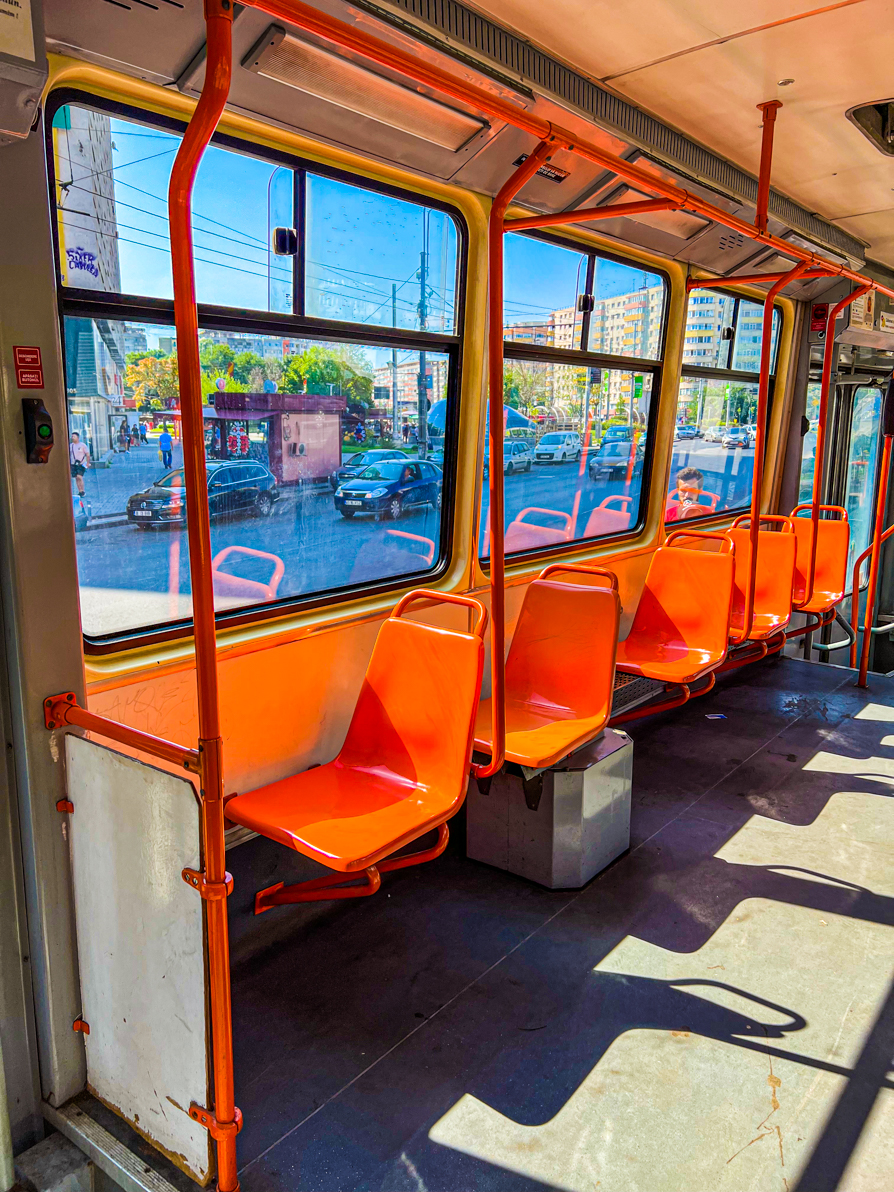 Image of interior of Bucharest tram with orange, empty, single seats on side