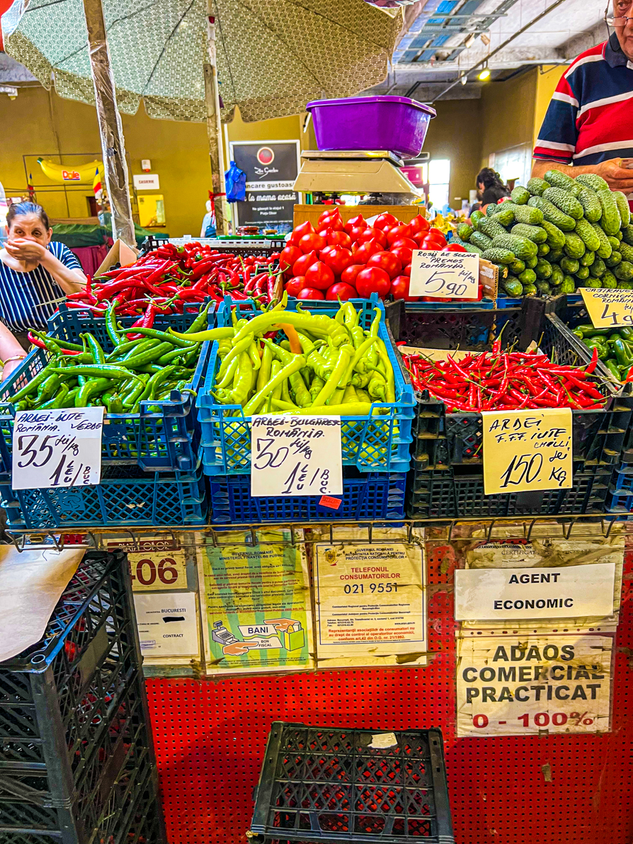Another stall inside the Obor market in Bucharest showing green, yellow and red chillies in black and blue baskets.