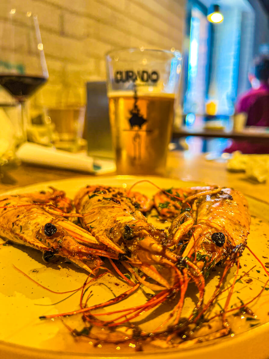 Image of three giant prawns at front with Curado beer in background in Curado Cardiff Wales