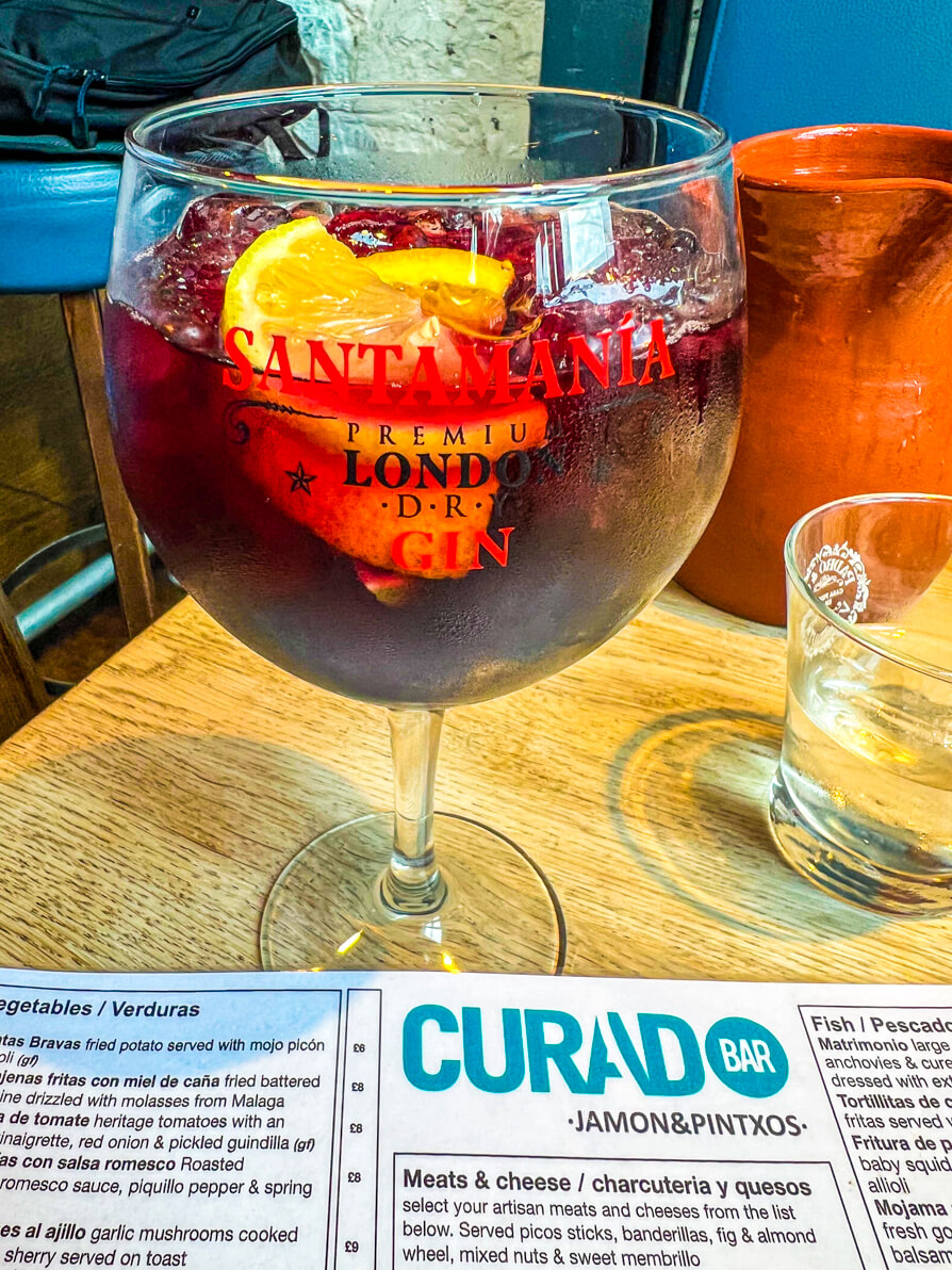 Image of glass of red sangria on top of Curado menu in Curado Cardiff Tapas Restaurant 
