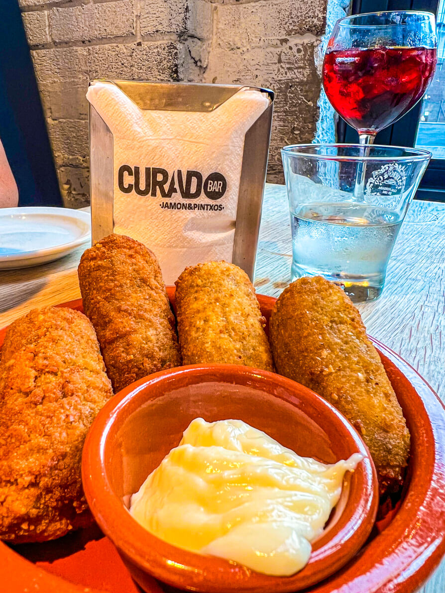 Four ham and cheese croquettes with Aioli and Curado napkins in the background in Curado Cardiff Wales