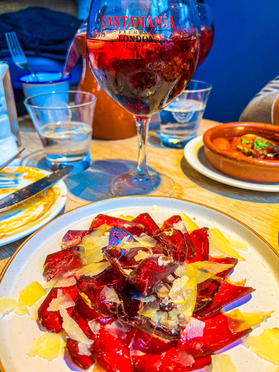 Image of Jamon Iberico in a flower shape with sangria in background in Curado Cardiff Wales