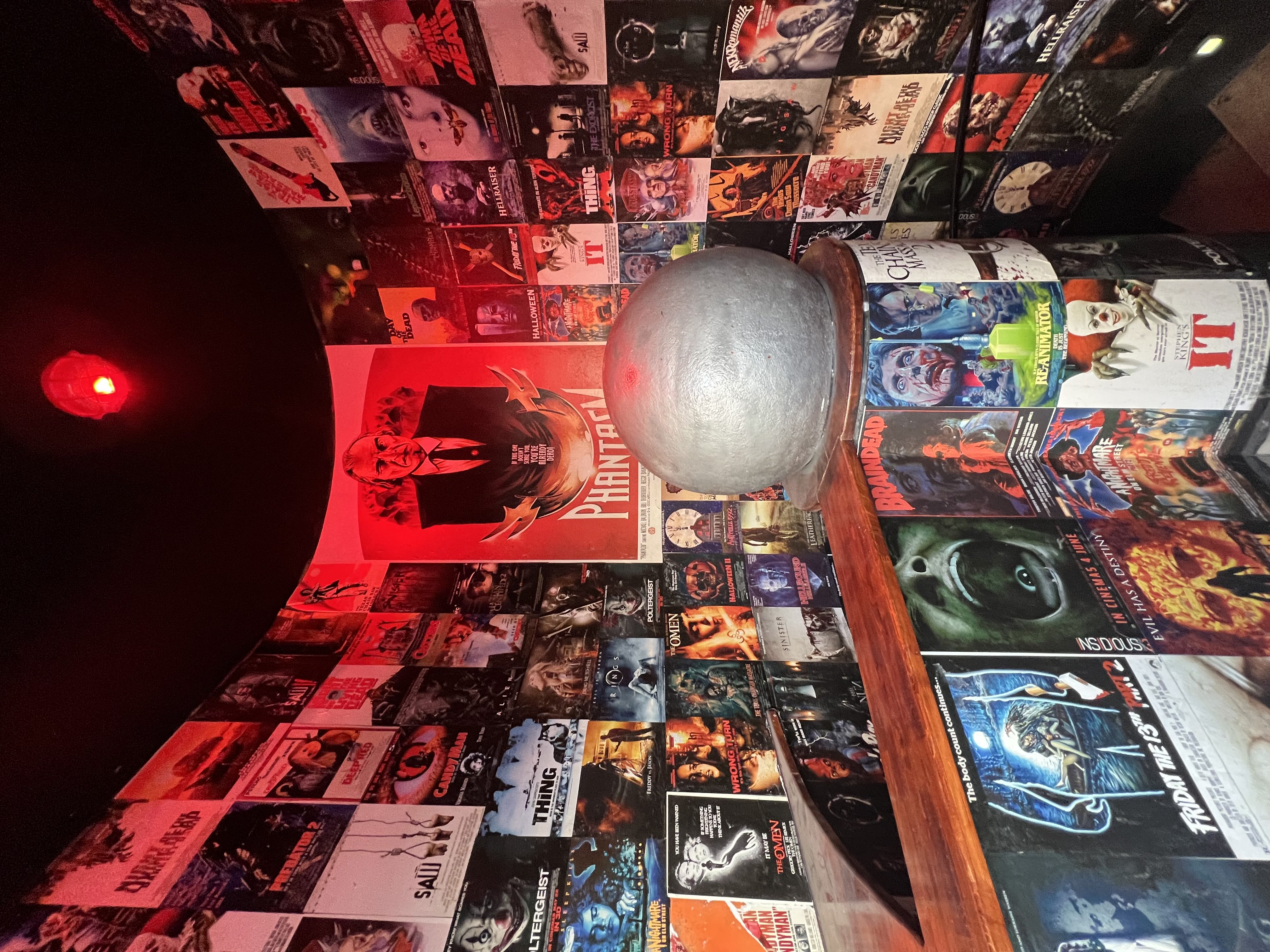 Image of entrance to Horror Bar Prague with dozens of horror posters on the walls before the spiral stairs to the bar