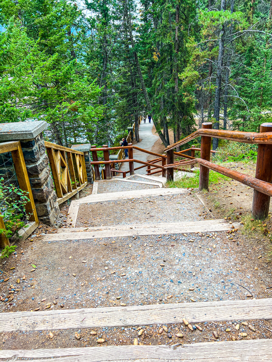 Set of stairs in background of Bow Falls Trail path in Banff Canada flanked by green trees