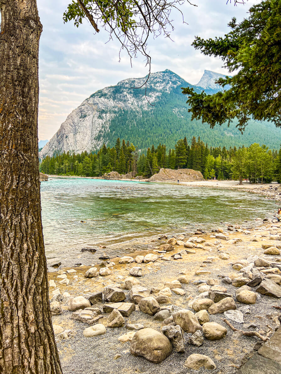 Image of Bow river, rocks, sand and Mt Rundle in background in Banff National Park