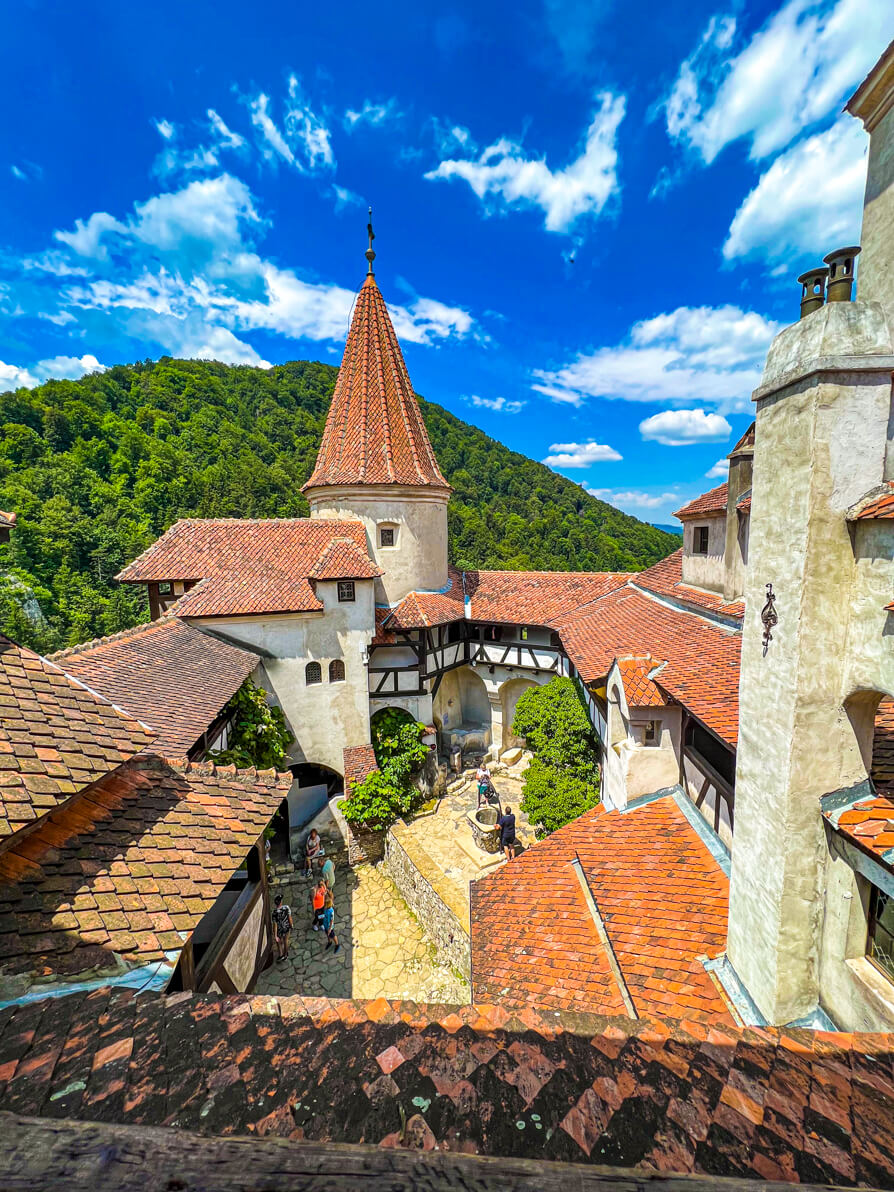 image of Bran Castle courtyard with Carpathian Mountains and blue sky in background
