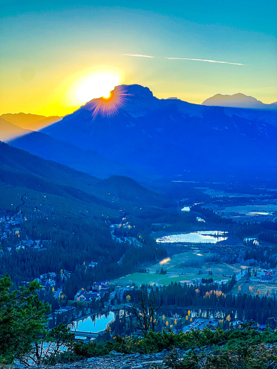 Image of Banff town and Rocky mountains in background and sun setting on the blue sky in Banff